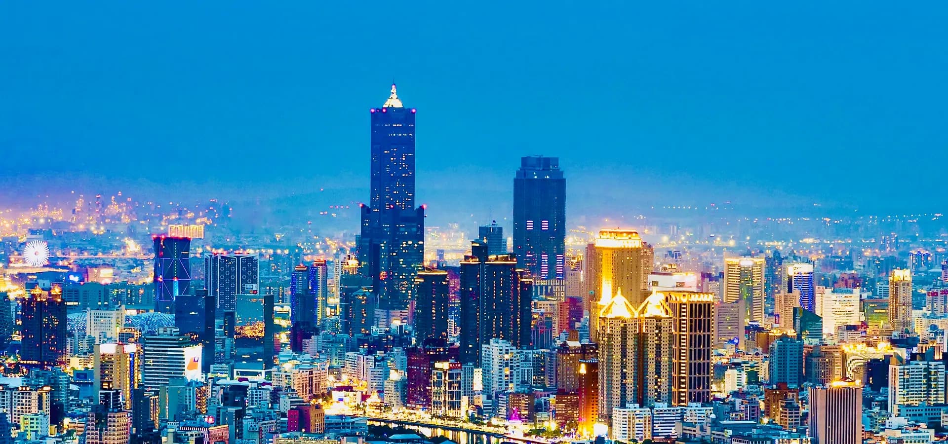 Skyline von Kaohsiung zur blauen Stunde, der 85 Sky Tower ragt über beleuchtete Hochhäuser und den Love River