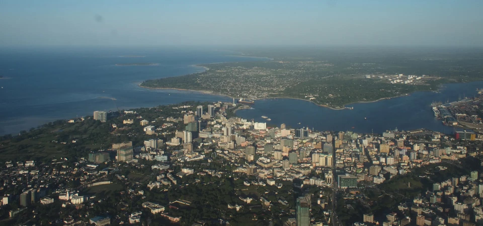 Vista aérea de los rascacielos y el puerto del centro de Dar es Salaam junto al azul océano Índico bajo un cielo despejado