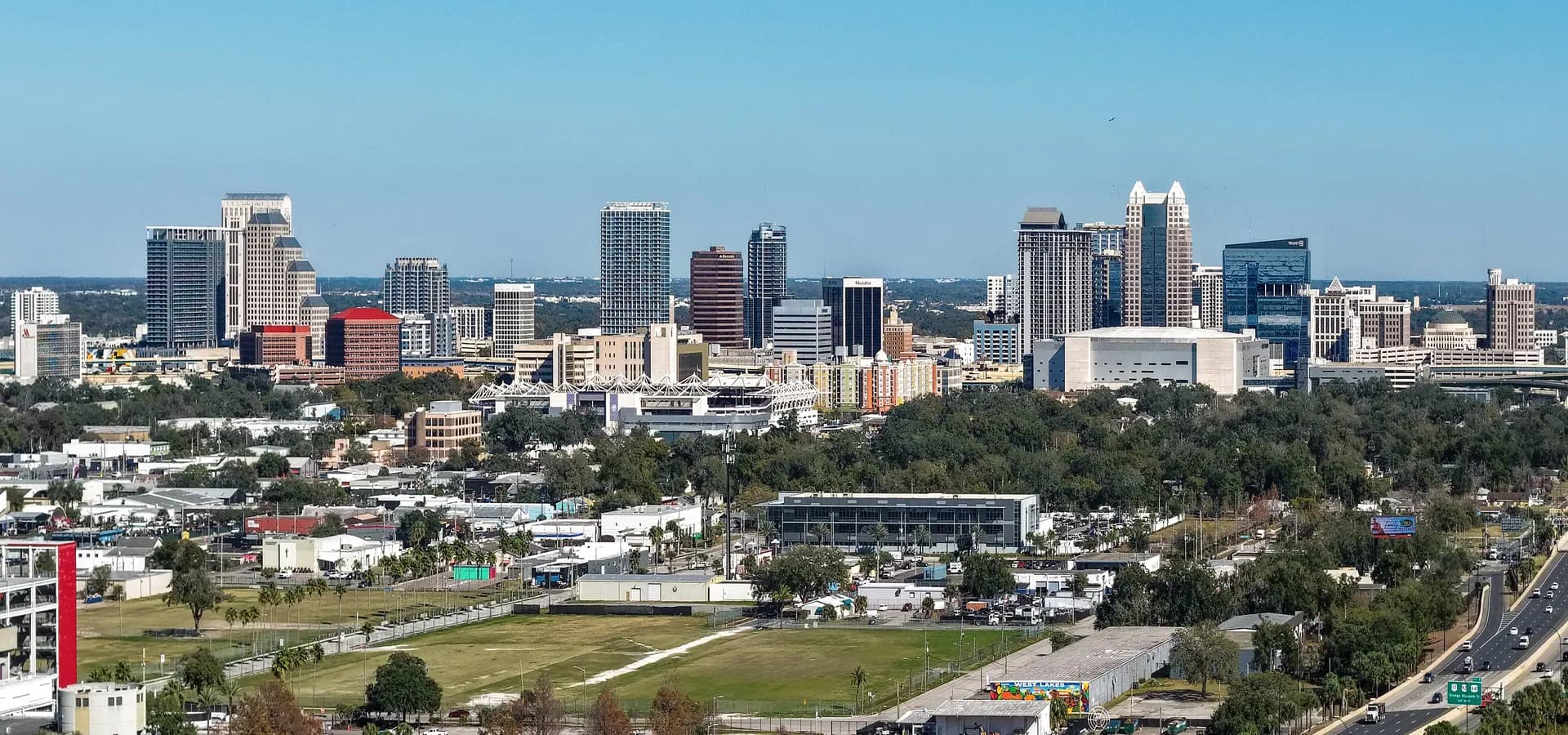 Horizonte do centro de Orlando se erguendo sobre um mar de árvores verdes sob um céu azul limpo