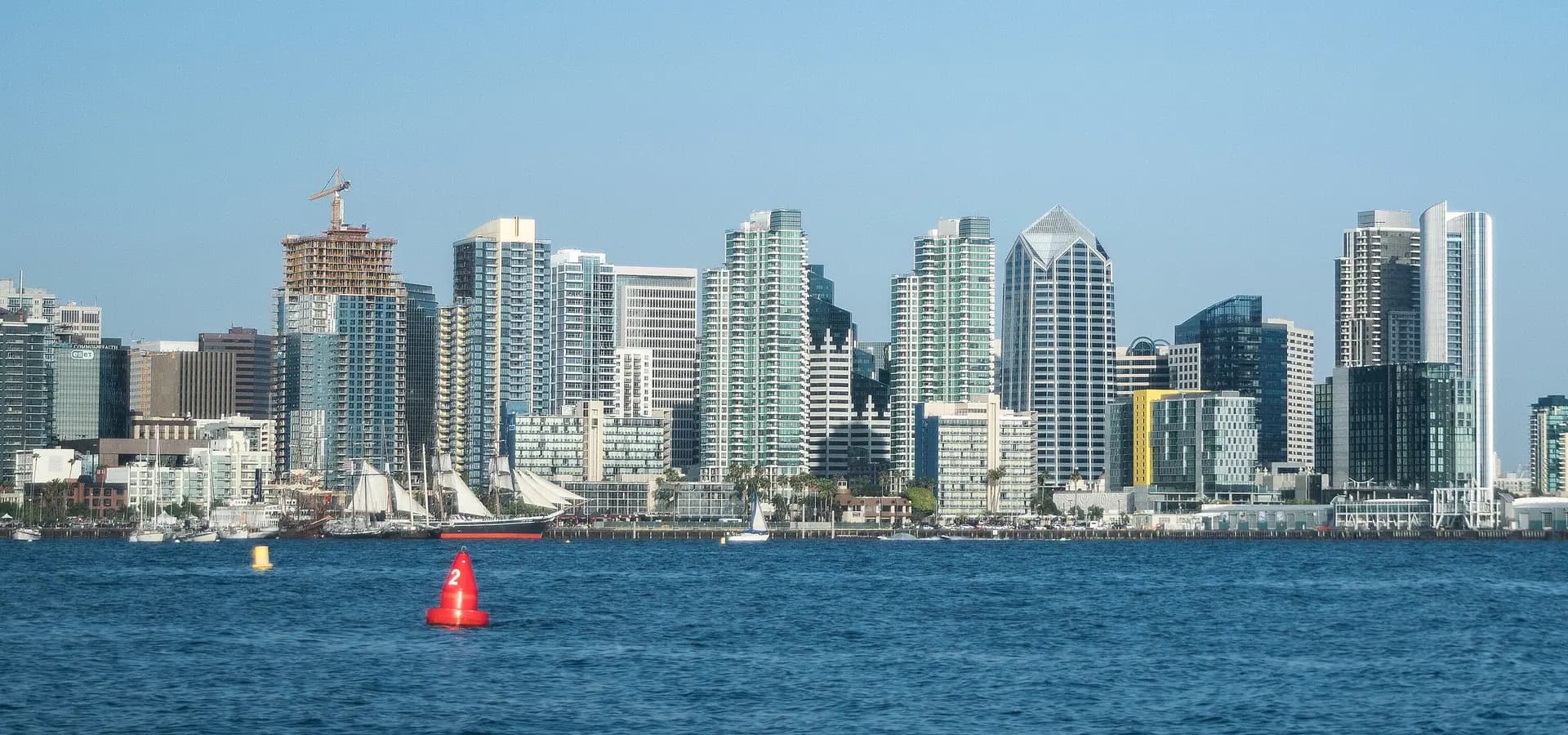 Hochhäuser der Innenstadt von San Diego und Segelschiffe an der Uferpromenade, gesehen über das blaue Wasser der San Diego Bay
