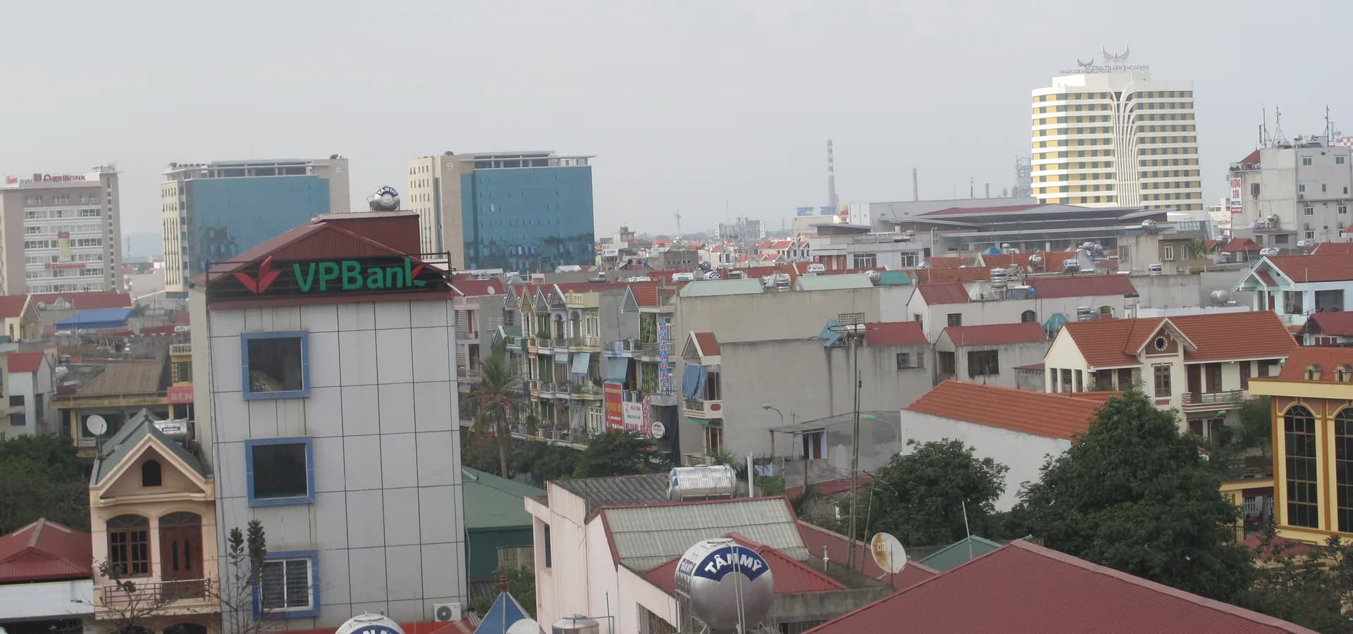Casas de techo rojo y torres de mediana altura en el centro de Bắc Giang bajo un cielo pálido